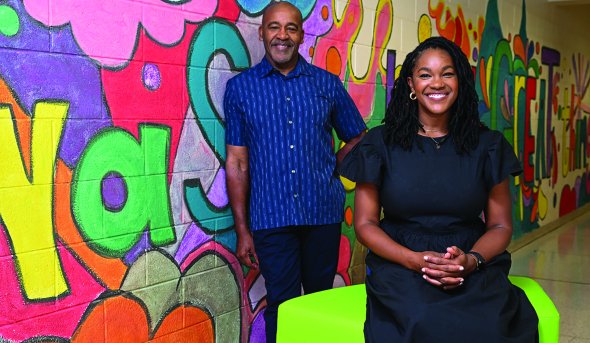 a man and woman stand in front of colorful wall 