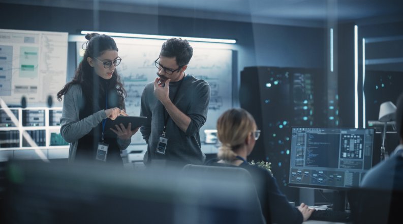 People in a computer lab looking at a tablet