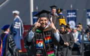 A student wearing a robe and mortarboard celebrates.