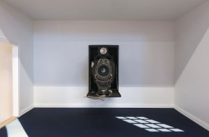 Photo of a camera inside a dollhouse room.